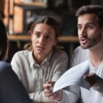 Annoyed angry disappointed customers clients couple holding paper arguing with bank manager fight complain on bad contract terms high mortgage rate demand claim insurance compensation meeting lawyer