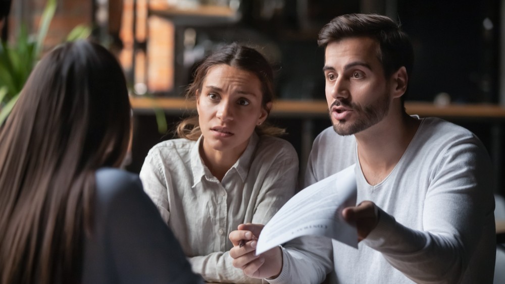 Annoyed angry disappointed customers clients couple holding paper arguing with bank manager fight complain on bad contract terms high mortgage rate demand claim insurance compensation meeting lawyer