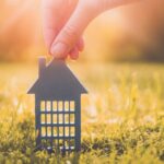 Model of gray apartment house on autumn yellow grass on a sunny day. Conceptual symbol of renting, hostel and student housing.
