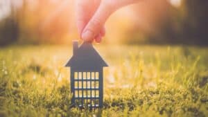 Model of gray apartment house on autumn yellow grass on a sunny day. Conceptual symbol of renting, hostel and student housing.