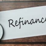 Selective focus of magnify glasses, pen, flower and notebook written with REFINANCE.