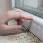 Person checking window seal for property maintenance and insulation.