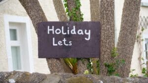 Holiday Lets sign, on tree advertising property to be rented. Air BnB and rentals are causing a housing crisis in many countries as locals and young people cannot get on the housing market.