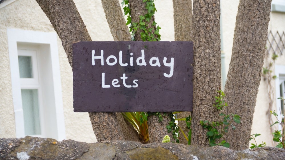 Holiday Lets sign, on tree advertising property to be rented. Air BnB and rentals are causing a housing crisis in many countries as locals and young people cannot get on the housing market.