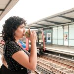 Young female commuter drinking coffee while waiting for the tube to arrive at a london underground station, enjoying a hot beverage during her daily commute