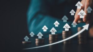Stacked coins with rising percent house icons and upward arrow symbolizing higher interest rates mortgage costs inflation and smart investment growth in digital finance era