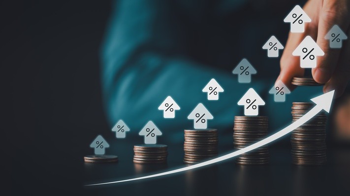 Stacked coins with rising percent house icons and upward arrow symbolizing higher interest rates mortgage costs inflation and smart investment growth in digital finance era