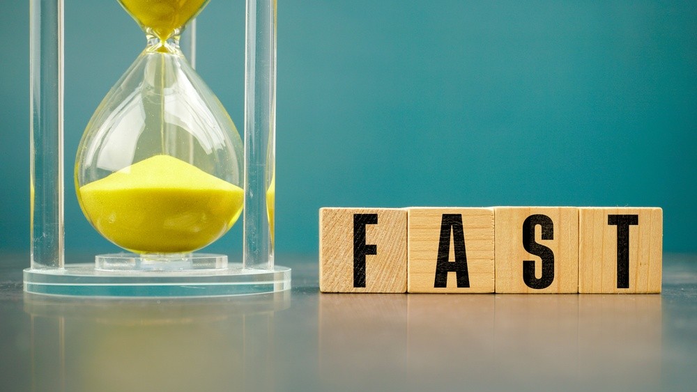 Yellow hourglass beside wooden blocks spelling FAST, representing speed, efficiency, productivity, quick decisions, time management, business performance, and rapid execution.