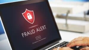 Fraud alert warning on laptop screen with shield and lock icon.